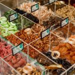 A vibrant selection of dried fruits in transparent containers at a market stall.