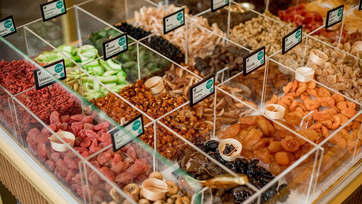 A vibrant selection of dried fruits in transparent containers at a market stall.
